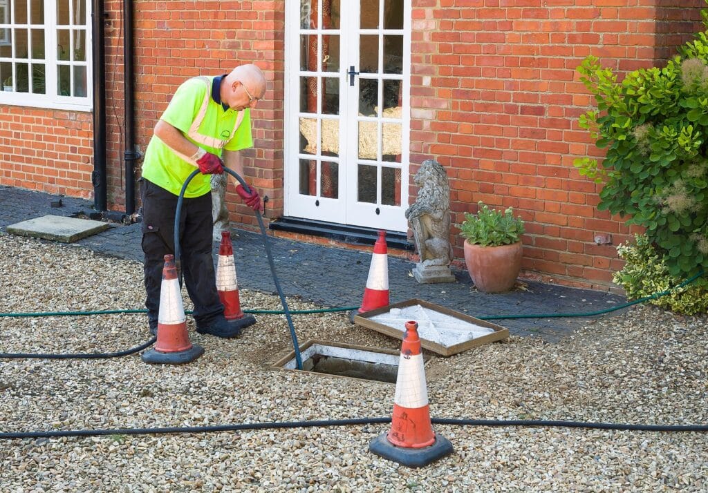 Man Jetting Sewage Drain Outside House