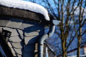 Surface water drainage. House gutter covered in snow.