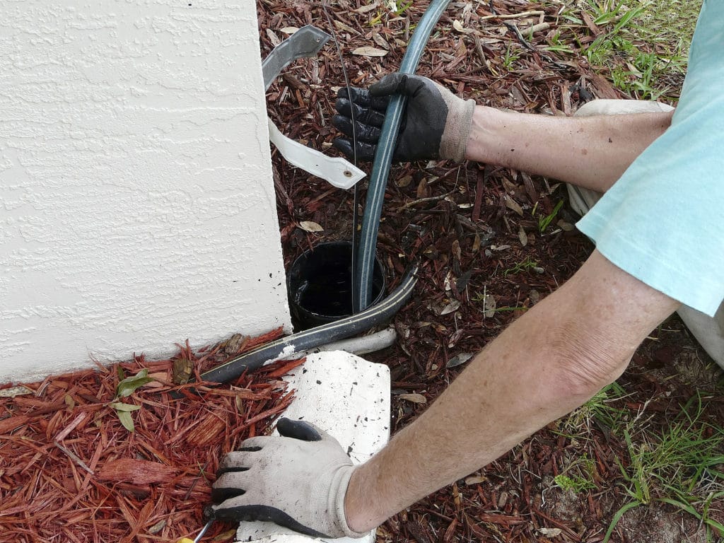 Homeowner using a sewer snake in outside drain