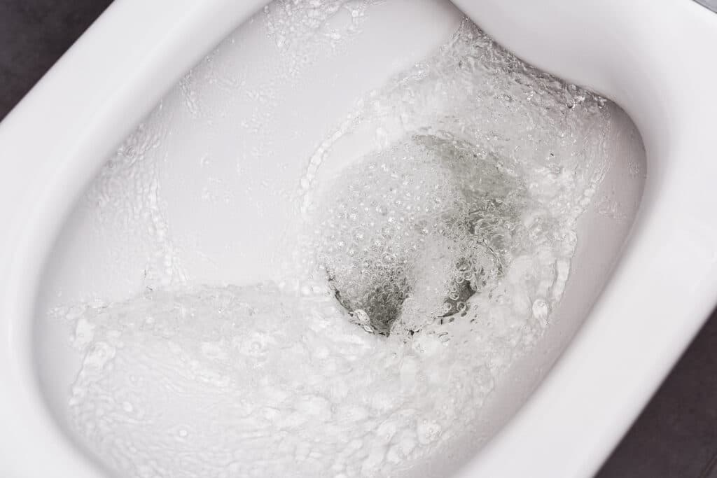 a toilet being flushed so the bowl is full of water