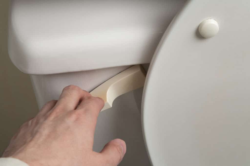 closeup of a toilet handle being pulled