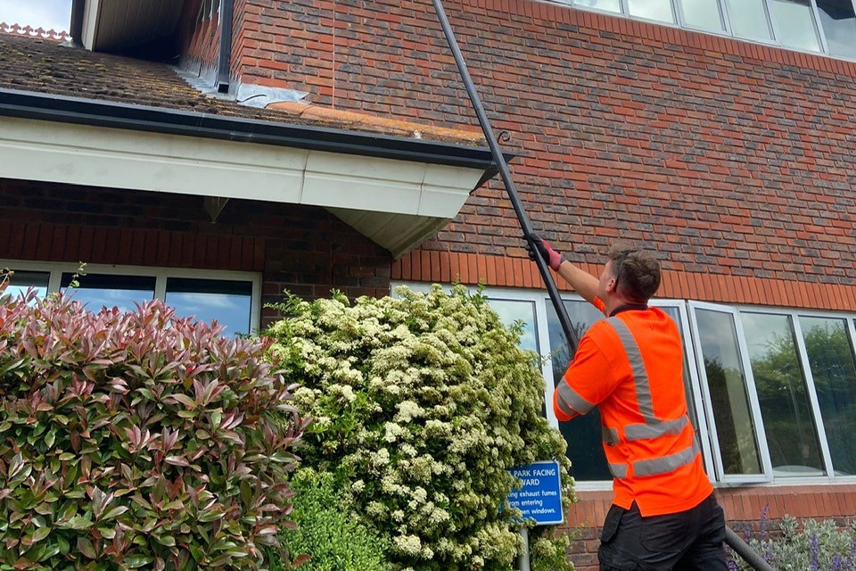 a man cleaning gutters using extendable vacuum