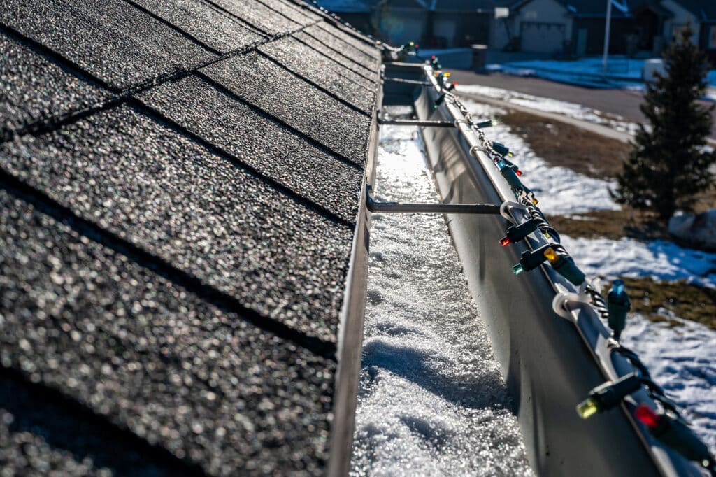 Ice and snow building up inside a rooftop gutter system on a residential house